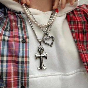Image of a customer wearing two necklaces: The Venomous Love Chain with a heart-shaped snakeskin-patterned pendant, and The Colossal Cross Chain, featuring a substantial cross pendant on a Stainless Steel chain.